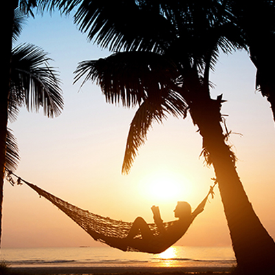 A person in a hammock on the beach.