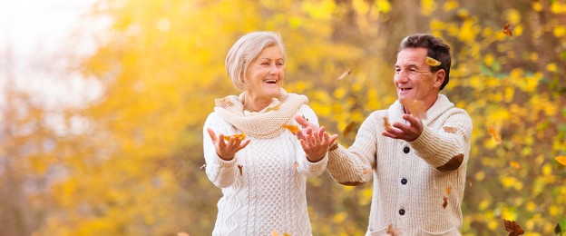 senior couple laughing outdoors with autumn leaves