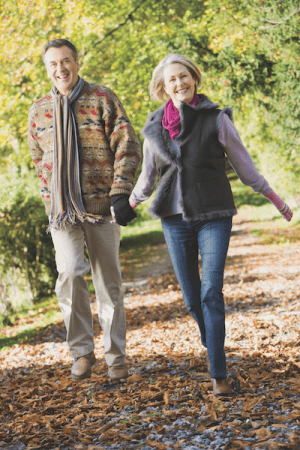 Happy couple walking in autumn leaves.