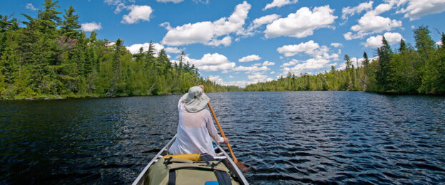 Person canoeing on a scenic lake.